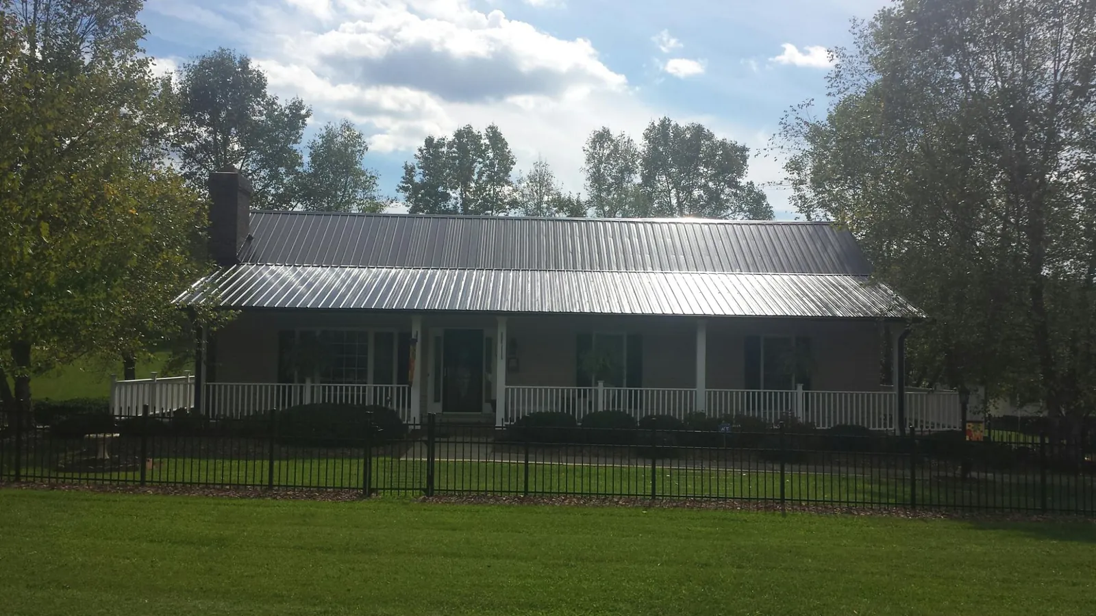 Gray metal roof on a brick ranch with a full width front porch — Gutter Guard Installation work by our crew in Roper