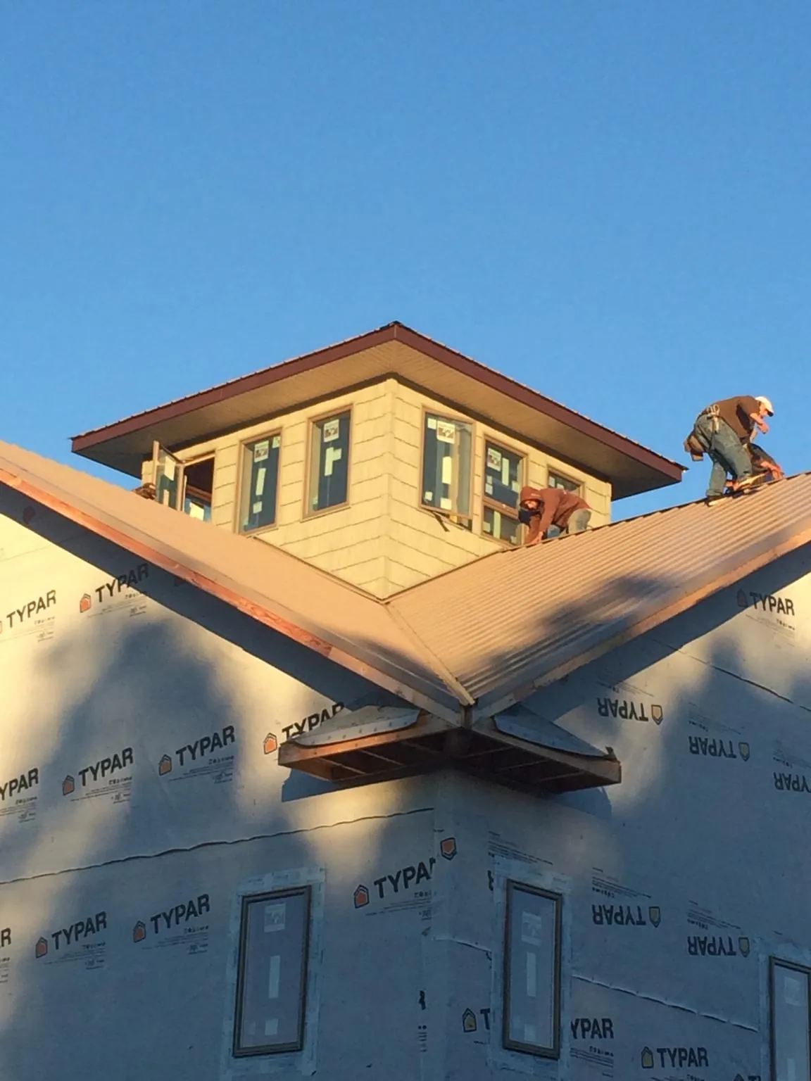 Roofers working around a rooftop cupola on a new metal roof at sunset — Roof Waterproofing in Roper by Roofing Brothers